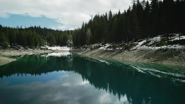 Landscape of reflecting turquoise Lake Cauma with forest trees with blue cloudy sky in Switzerland