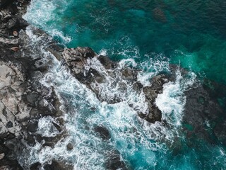 waves hitting rocks and cliffs in the sea, viewed from above