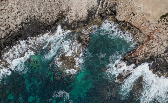 Aerial view of a pristine stretch of crashing waves of the ocean against the rocky shoreline © Drone Produktion/Wirestock Creators