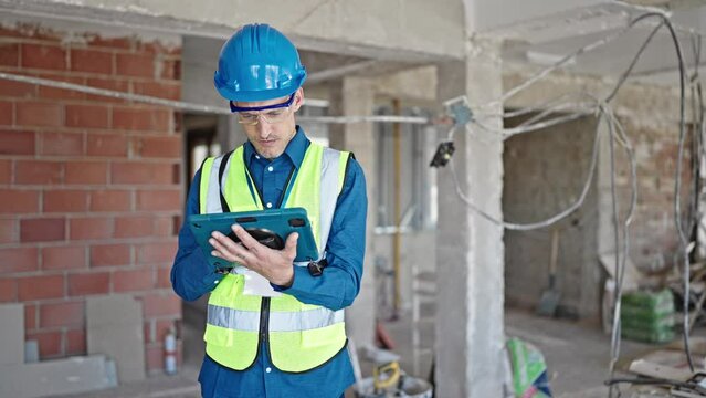Two men builders reading document using touchpad shake hands at construction site