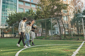 Three young male and female college models walking with a ball and chatting after the game on a college futsal field in the fall in South Korea, Asia.