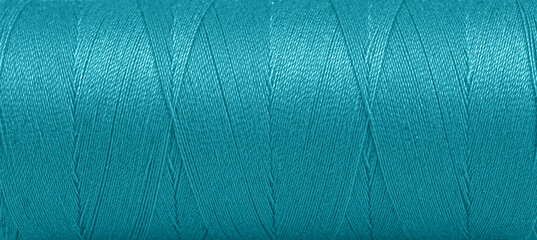 Texture of threads in a spool of turquoise color on a white background