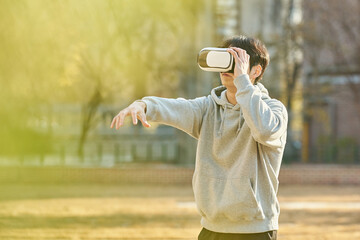 Young college student male model wearing 3D glasses and experiencing virtual reality in an outdoor...