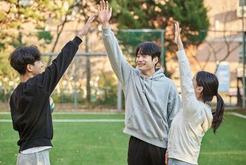 Three young male and female college models walk with a ball and raise their hands in celebration...