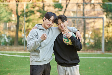 Young male college students pose for a post-match shoulder rub at a university futsal field in South Korea, Asia