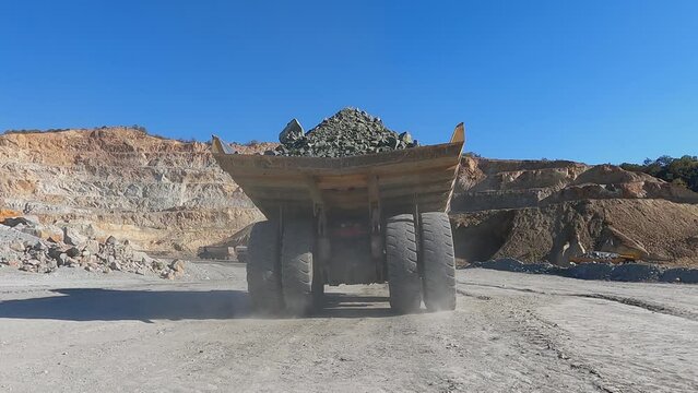 Heavy mining dump trucks driving along the opencast open mine pit, slow motion
