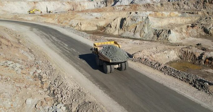 Large quarry dump truck transporting ore on open pit mine, aerial slow motion shot