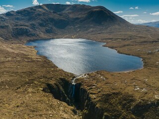 a mountain near a lake surrounded by grass and rocks in the middle of nowhere
