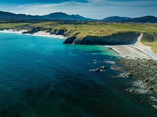 Fototapeta na wymiar an aerial view of a sandy beach and blue waters with grass on either side
