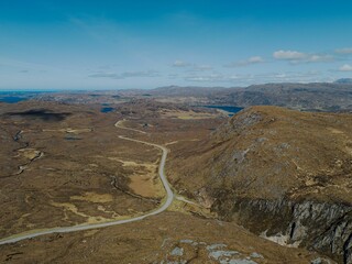 road going through the mountains towards a lake and a distant valley