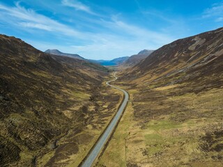 an aerial view of a winding road in the highlands of scotland