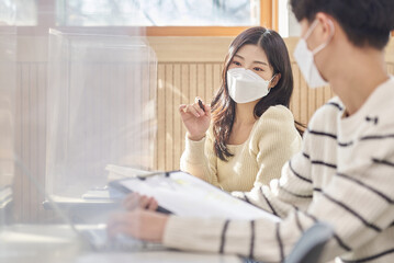 Obraz premium Young Asian college and university students, male and female models, studying or discussing in class while wearing masks in a university classroom during the Asian Korean Pandemic.