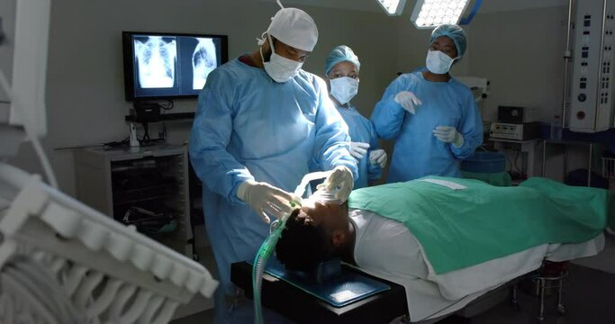 Diverse surgeons giving anesthesia to patient in operating theatre, slow motion