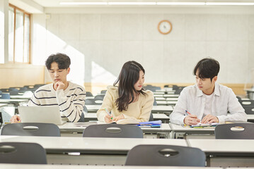Three young Asian college students, both male and female, are in a classroom in South Korea where they are either teaching or studying