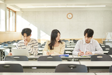 Three young Asian college students, both male and female, are in a classroom in South Korea where they are either teaching or studying