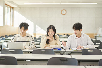 Three young Asian college students, both male and female, are in a classroom in South Korea where they are either teaching or studying