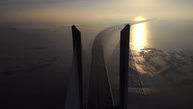 Aerial drone view of Vasco da Gama bridge in Lisbon, Portugal, sunrise with sun light and reflections