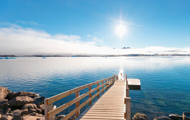 Midnight Sun concept with night time in the northern hemisphere  - Tasiilaq wooden pier on coast - Greenland