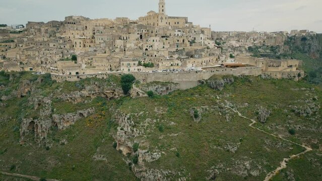 Aerial footage of Murgia National Park with ruined stone buildings and caves on a hill