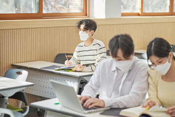 In a higher education classroom in South Korea, young university students wearing masks are...