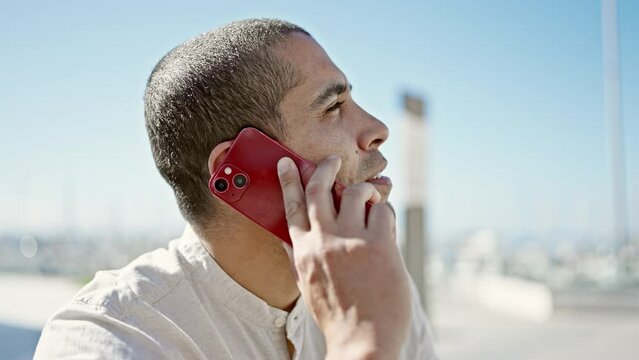 Young hispanic man speaking on the phone at street