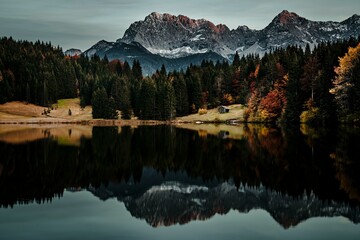 Scenic view of a tranquil lake surrounded by green trees and snowy mountains in Bavaria, Germany