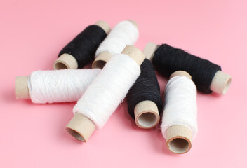 Black and white sewing threads on pink background