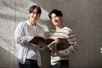 Young male college student models leaning against the wall of a university lecture hall in a...