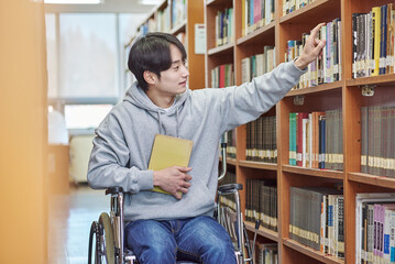 Asia South Korea university library bookcase in a wheelchair looking for a book on the shelf, physically handicapped young disabled male college student model