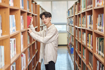 Young variously facial expression male college student model looking for and reading a book on a shelf in a university library in Asia South Korea