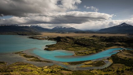 Obraz premium Scenic view of a lake surrounded by green mountains on a cloudy day