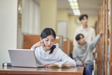 Asian Korean university library desk chair woman sitting on laptop and reading book and man helping...