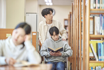 Asian Korean university library desk chair woman sitting on laptop and reading book and man helping...