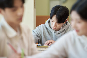 Two young college student man and woman couple model and solo male model looking at laptop and book together in library of Asian Korean university
