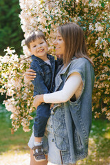 Caucasian family, mom and little son hug and have fun on a walk in the park in summer. Mother's Day