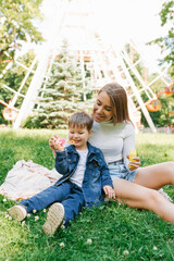 Happy little boy is playing, blowing soap bubbles together with his happy young mother. Weekend breaks, caring parenting and child care