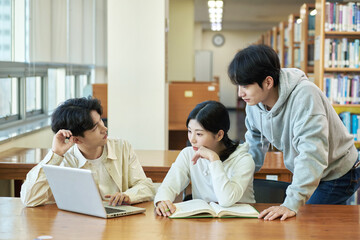 Two young college student man and woman couple model and solo male model looking at laptop and book together in library of Asian Korean university