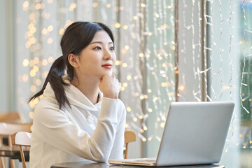 Young female college student model sitting at a cafe table in Asian Korea, listening to a lecture,...