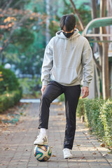 Young Asian Korean college student male model wearing a mask and standing with his feet on a soccer...