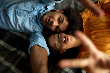 Upper view image of cute youthful lovey couple doing selfie lying on back opposite each other head...