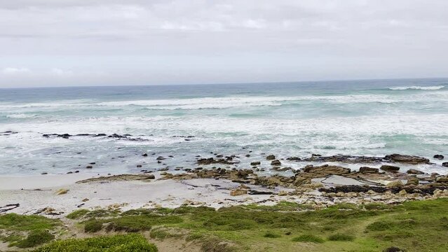 Foamy waves of the sea hitting the rocky shore under the cloudy sky