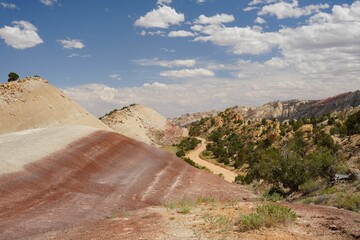 Scenic desert landscape with hills and a bright blue sky with white clouds scattered throughout