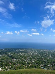 Aerial view of an island surrounded by crystal blue ocean water and white fluffy clouds in the sky