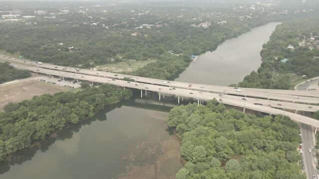 Drone view of traffic cars driving on CTRMA board bristles bridge over a river with trees in Texas