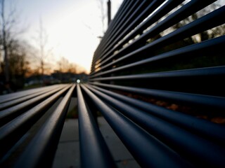 Black metal outdoor bench located on a sidewalk