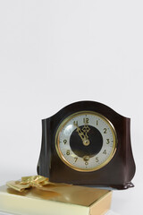 Table vintage clock and a gift in a golden package with a bow on a white background