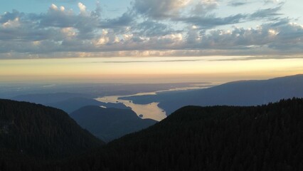 Mesmerizing view of a river through mountains and evergreen pine trees at sunset