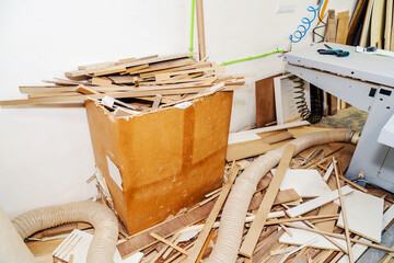 A cardboard box with wooden waste in a small, furniture workshop. Close up