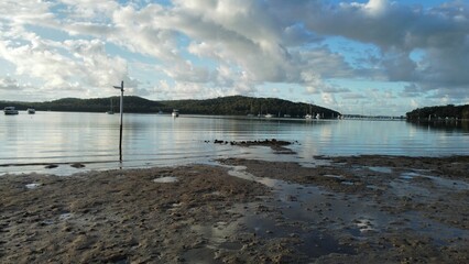 a beach in front of the water and trees with boats