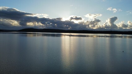 a body of water surrounded by clouds in the sky and mountains